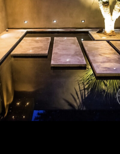 Elegant outdoor space with water feature and stepping stones illuminated at night.