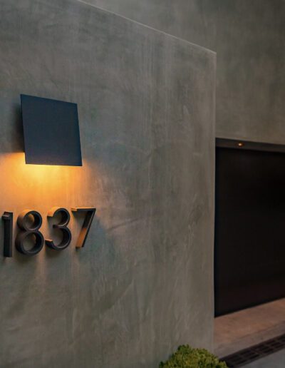 Modern house facade with illuminated address number 1837 at dusk.