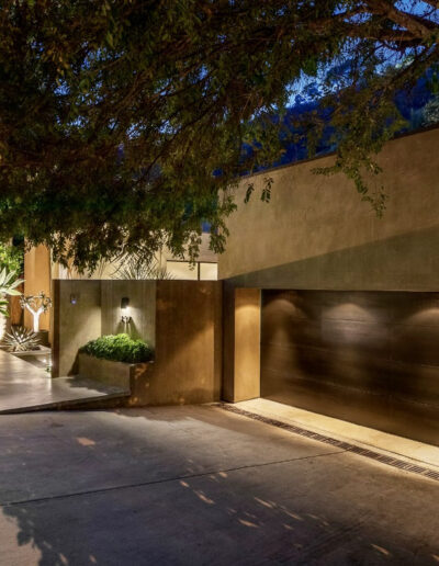 Modern house exterior at dusk with illuminated pathway and garage door.