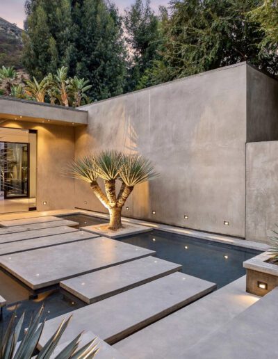Modern backyard with concrete stepping stones over a sleek pool, surrounded by desert-style landscaping.