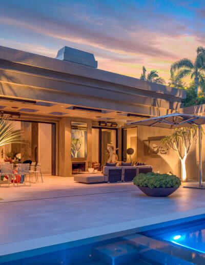 Luxurious modern home exterior at twilight with illuminated living spaces and pool.