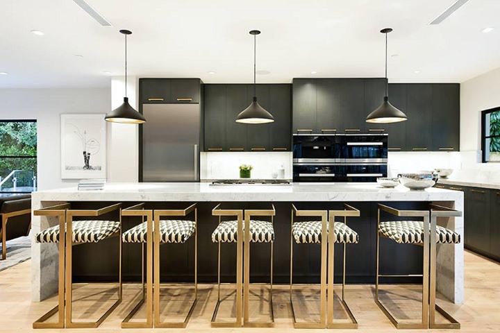 Modern kitchen with black cabinetry, pendant lights, and a central island with bar stools.