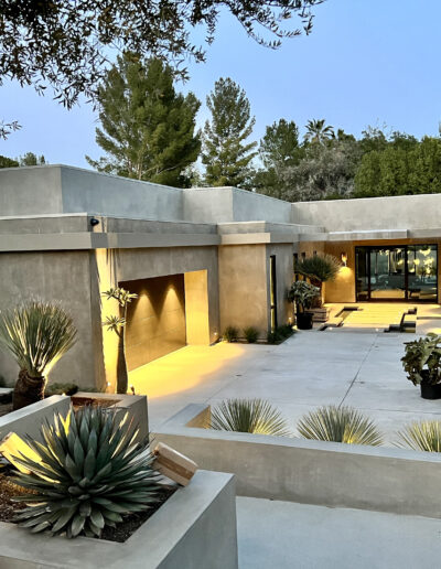 Modern home entrance at dusk with architectural lighting and desert landscaping.