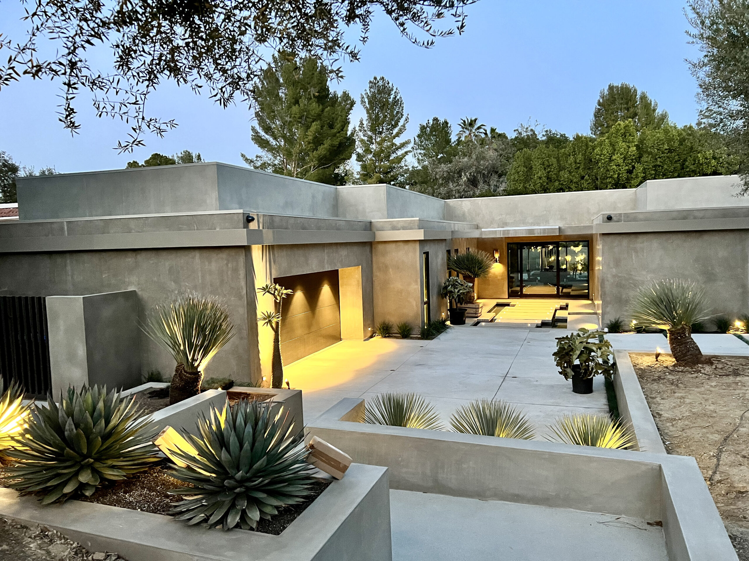 Modern home entrance at dusk with architectural lighting and desert landscaping.